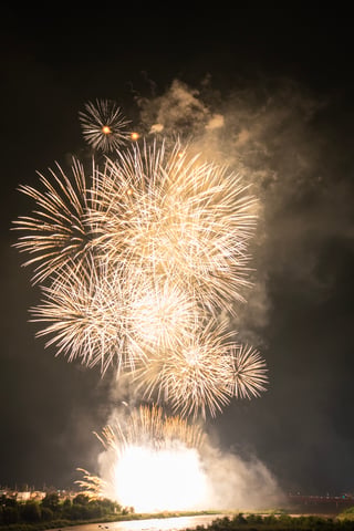 A fireworks display over a body of water, with a boat in the foreground and a crowd of people watching.