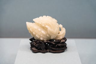 A white and black carved stone sculpture of a fish on a black base, with water droplets on the fish's body.