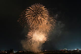 A fireworks display in the night sky, with bright lights illuminating the sky and city below.