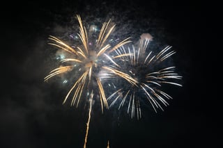 A fireworks display in the night sky, with bright fireworks and a long stream of light.