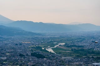 A cityscape with a river, mountains, and a street lamp in the foreground.