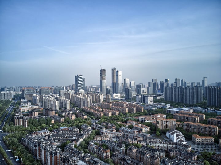 A bustling cityscape with tall buildings, a river, and a bridge, showcasing a blend of urban and natural elements.