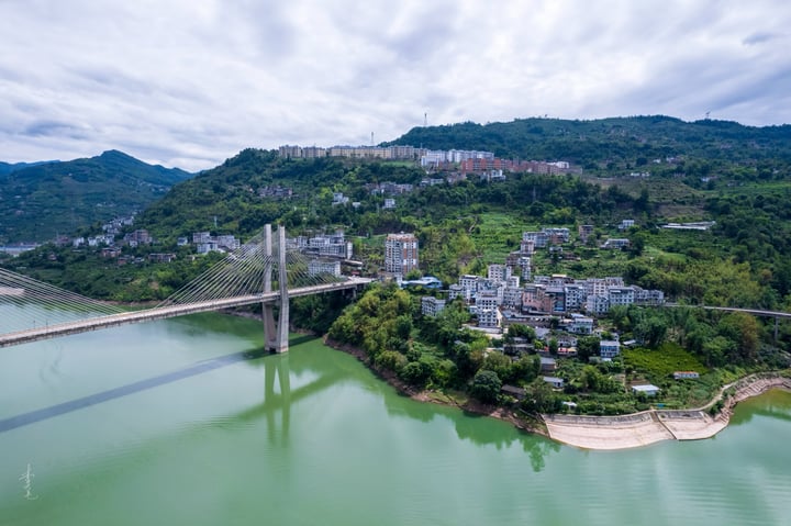 An aerial view of a city nestled between mountains, with a large body of water in the foreground and a cityscape in the background.