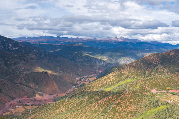 A breathtaking mountainous landscape with a valley, a winding river, and a blue sky with clouds.