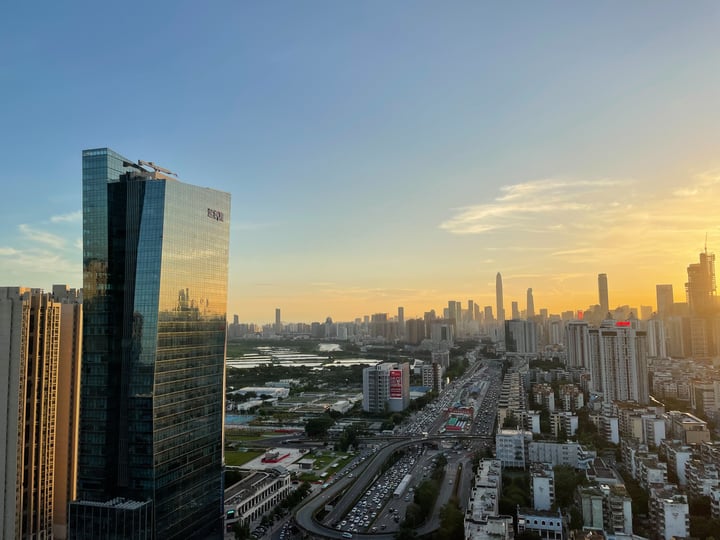 A city skyline at sunset, with tall skyscrapers and a river in the background.