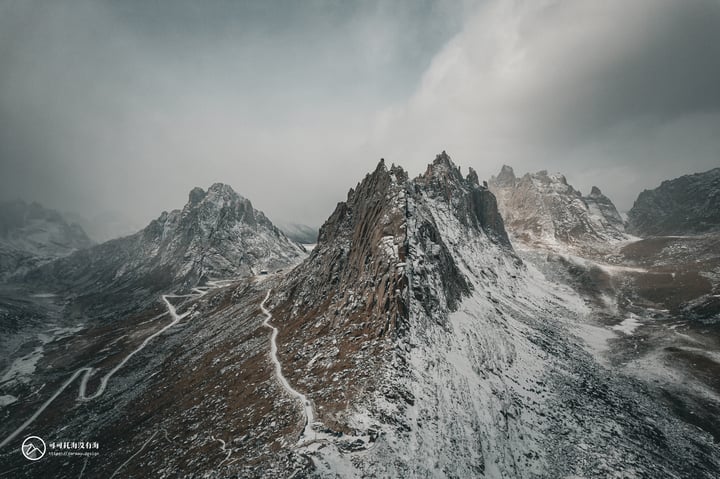 A snowy mountain range with snow-covered peaks and a winding road through the snow-covered landscape.