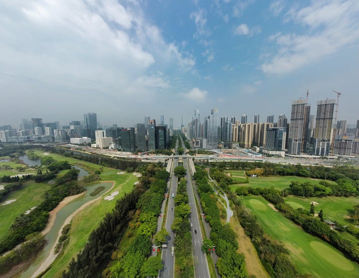 A cityscape with skyscrapers and a park is captured from an aerial perspective, showcasing the blend of nature and urban development.