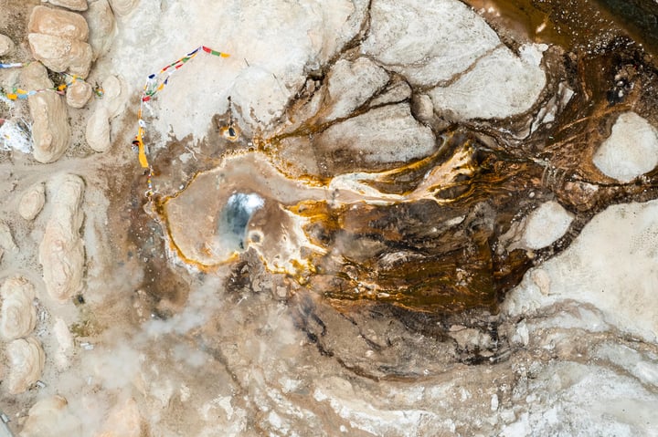 An aerial view of a rocky landscape with a large, golden-colored hole in the center, surrounded by rocks and dirt.