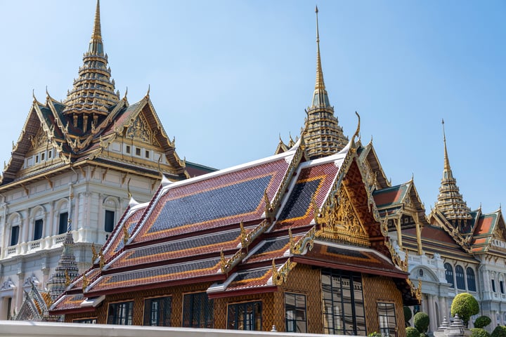 The image showcases the Grand Palace of Wat Phra in Bangkok, Thailand, with its ornate architecture and solar panels.