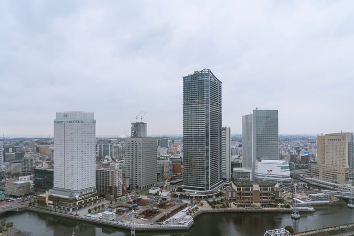 A cityscape with tall buildings, a river, and a bridge, with a cloudy sky above.