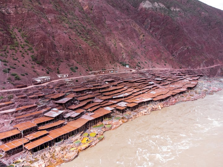 A traditional salt drying field in Markam, Tibet. Brine is placed in segmented salt drying pools, where the water gradually evaporates, leaving behind the salt. The brine, rich in minerals, gives the water a vermilion color.