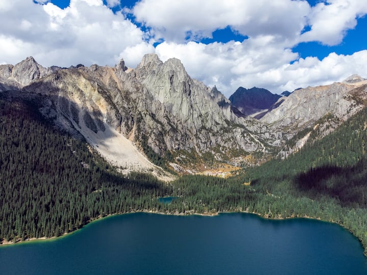 A breathtaking aerial view of a mountainous landscape with a serene lake in the foreground, surrounded by towering mountains and lush greenery.