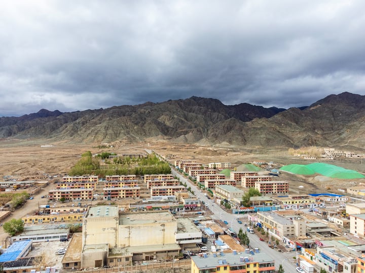 A mountainous area with a construction site in the foreground, surrounded by buildings and cars.