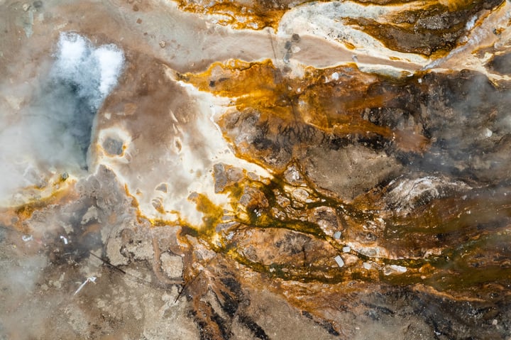 An aerial view of a landscape with a mix of brown and yellow hues, with a river flowing through it.