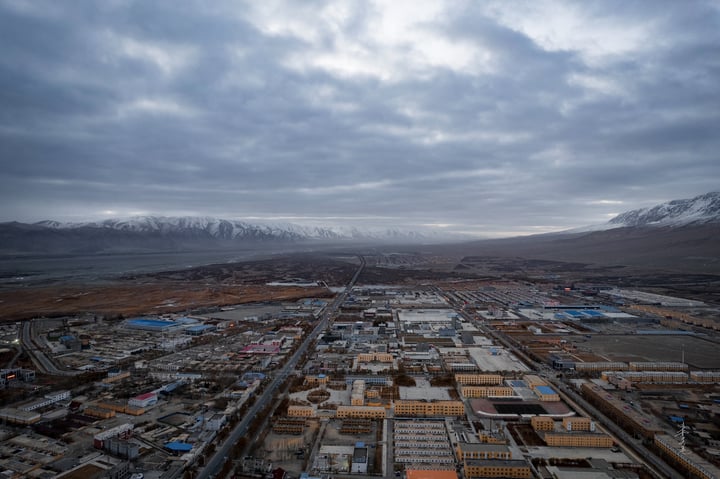 An aerial view of a city with a mix of buildings, roads, and mountains in the background.