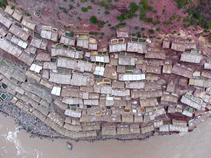 A traditional salt drying field in Markam, Tibet. Brine is placed in segmented salt drying pools, where the water gradually evaporates, leaving behind the salt. The brine, rich in minerals, gives the water a vermilion color.