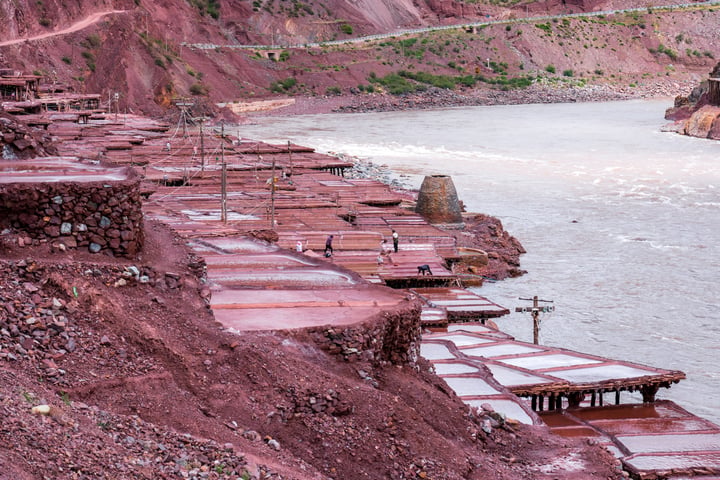 A traditional salt drying field in Markam, Tibet. Brine is placed in segmented salt drying pools, where the water gradually evaporates, leaving behind the salt. The brine, rich in minerals, gives the water a vermilion color.