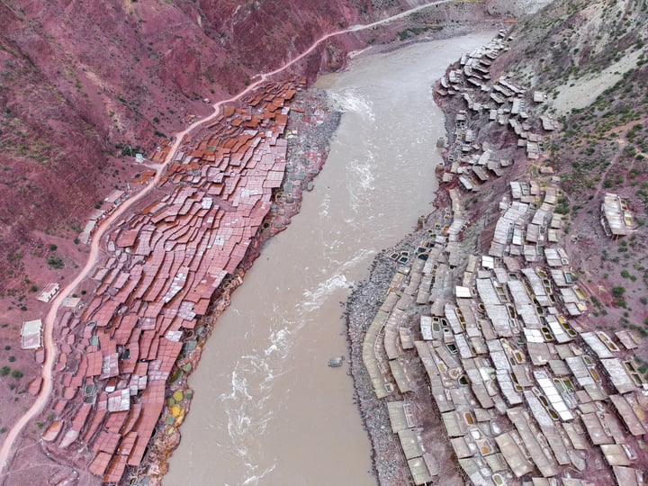 A traditional salt drying field in Markam, Tibet. Brine is placed in segmented salt drying pools, where the water gradually evaporates, leaving behind the salt. The brine, rich in minerals, gives the water a vermilion color.