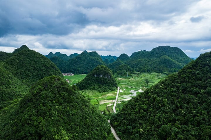 A serene mountain landscape with lush greenery, a winding river, and a small village in the distance.