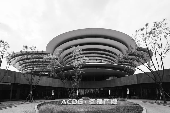 showcasing its modern architecture with a curved roof and large windows. The photo is taken from a low angle, emphasizing the building's grandeur. 