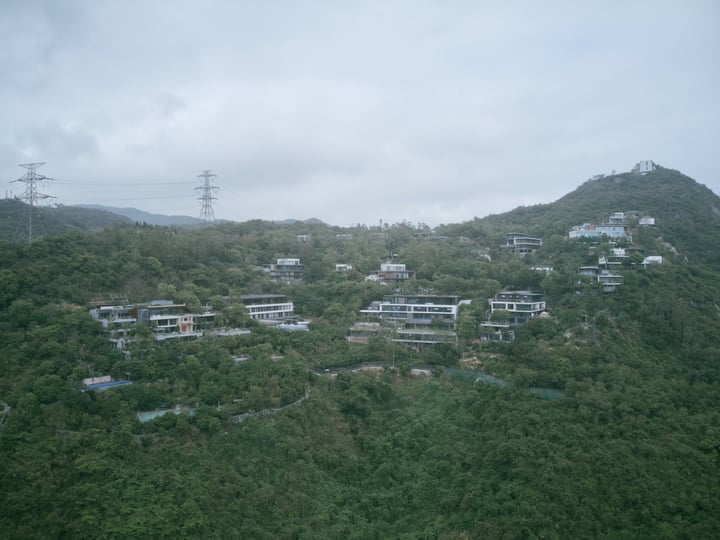 A mountain with houses, trees, and power lines on a hillside.