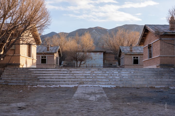 A small town with old brick buildings, a stone staircase, and bare trees in the background.