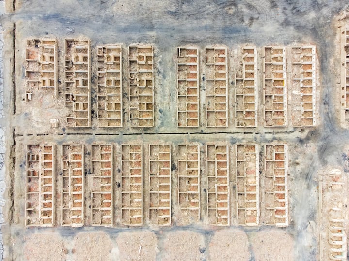 An aerial view of a brick wall with 24 rectangular brick panels, each with a grid of 12 rows and 4 columns, arranged in a grid-like pattern. The bricks are of varying shades of brown and are slightly cracked, giving the wall a rustic appearance.