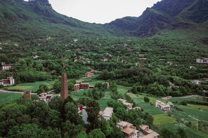 A serene mountainous landscape with a small village, surrounded by lush greenery, with a prominent brick tower in the center.