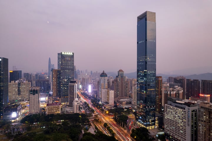 A cityscape with tall buildings, a busy road, and a hazy sky.