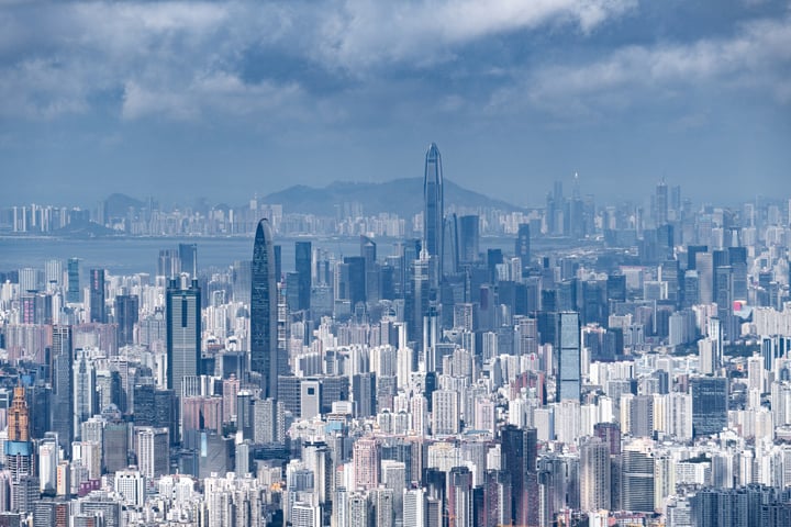 A panoramic view of a bustling cityscape with a mix of modern and older buildings, including a prominent skyscraper, is captured.