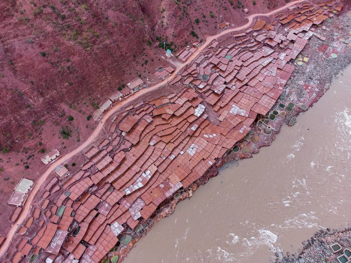 A traditional salt drying field in Markam, Tibet. Brine is placed in segmented salt drying pools, where the water gradually evaporates, leaving behind the salt. The brine, rich in minerals, gives the water a vermilion color.