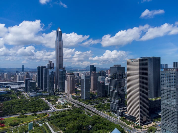 The image showcases the iconic World Trade Center in Hong Kong, with its towering skyscraper reaching towards the sky. The cityscape is densely populated with modern buildings, including skyscrapers and office buildings. The sky is a clear blue with fluffy white clouds, providing a serene backdrop to the bustling city. The image captures the essence of Hong Kong's urban landscape, showcasing its architectural diversity and bustling city life.