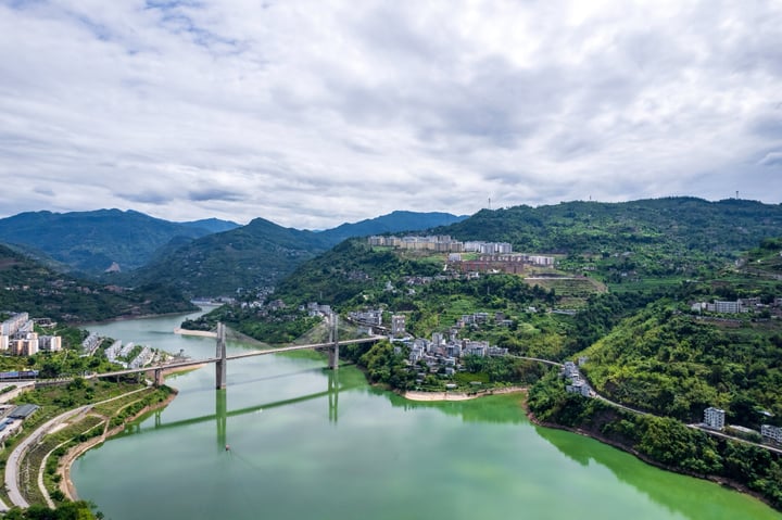 An aerial view of a city nestled between mountains, with a large body of water in the foreground and a cityscape in the background.