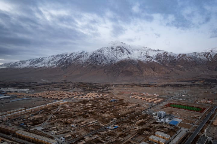 An aerial view of a city with a mix of buildings, roads, and mountains in the background.