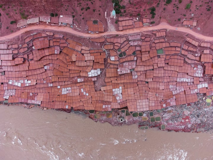 A traditional salt drying field in Markam, Tibet. Brine is placed in segmented salt drying pools, where the water gradually evaporates, leaving behind the salt. The brine, rich in minerals, gives the water a vermilion color.