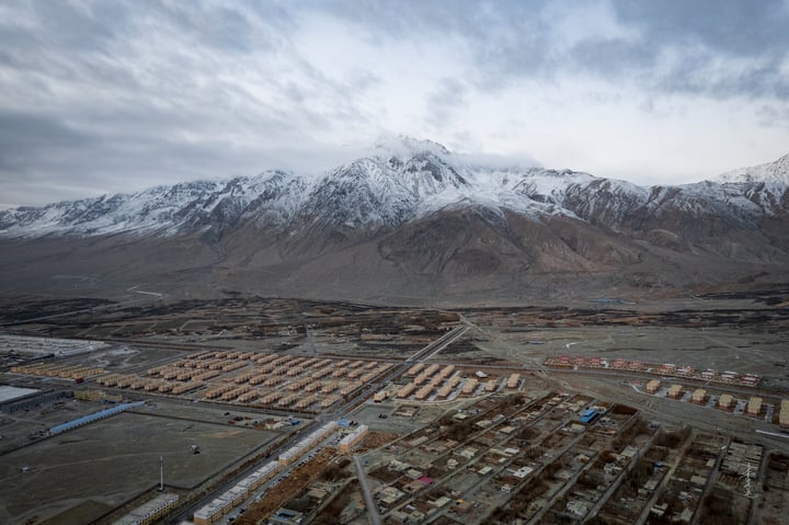 An aerial view of a city with a mix of buildings, roads, and mountains in the background.