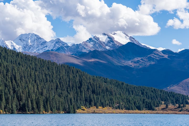 A serene mountain landscape with snow-capped peaks and a calm lake reflecting the sky.