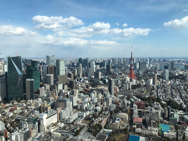 A bustling cityscape with a red and white Tokyo Tower in the background, surrounded by tall buildings and skyscrapers.