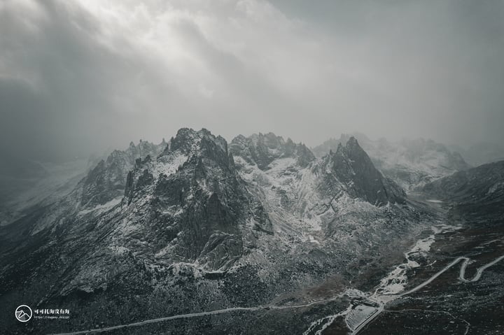 A snowy mountain range with a winding road in the foreground.