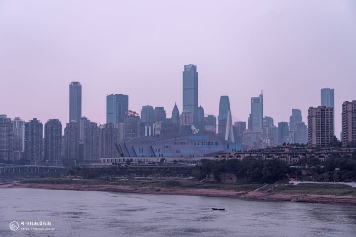 A cityscape with tall buildings, a river, and a boat on the river.