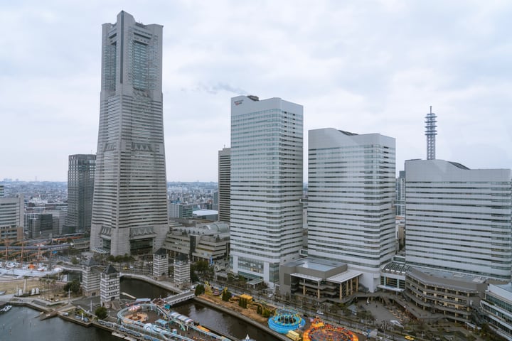 An aerial view of a cityscape with modern skyscrapers, a river, and a bridge, showcasing a blend of urban development and natural elements.
