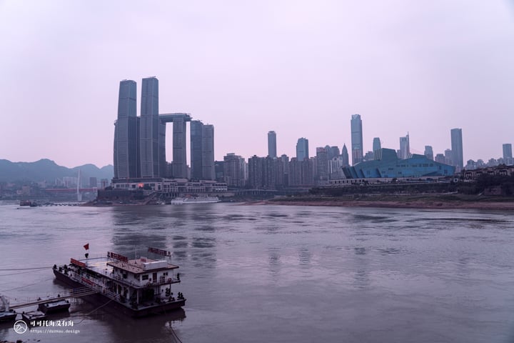 A serene cityscape with a large river, a ferry, and a tall building in the background.