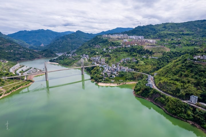 An aerial view of a city nestled between mountains, with a large body of water in the foreground and a cityscape in the background.
