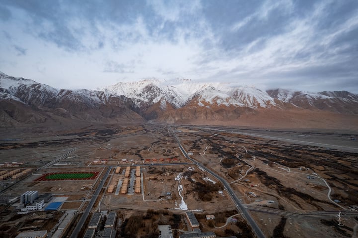 An aerial view of a city with a mix of buildings, roads, and mountains in the background.
