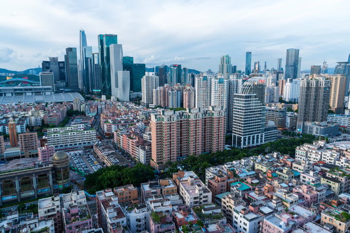 A panoramic view of a bustling city with tall buildings, a bridge, and a river, showcasing a harmonious blend of urban development and natural beauty.