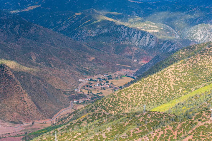A breathtaking aerial view of a valley surrounded by mountains, with a winding river and a small town in the valley.
