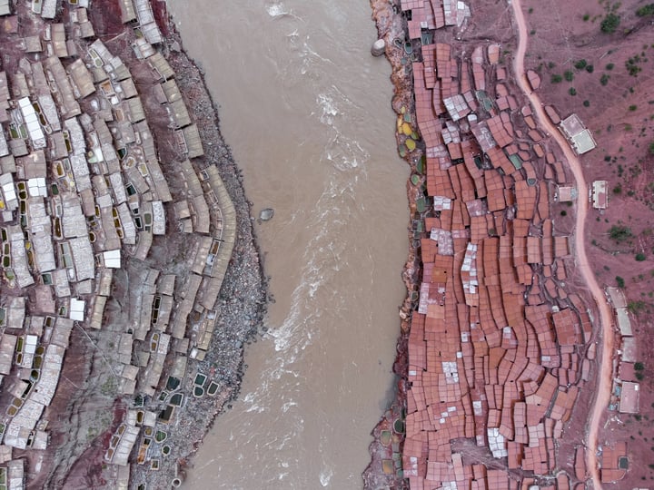 A traditional salt drying field in Markam, Tibet. Brine is placed in segmented salt drying pools, where the water gradually evaporates, leaving behind the salt. The brine, rich in minerals, gives the water a vermilion color.