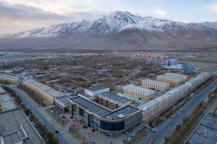 An aerial view of a city with a mix of buildings, roads, and mountains in the background.
