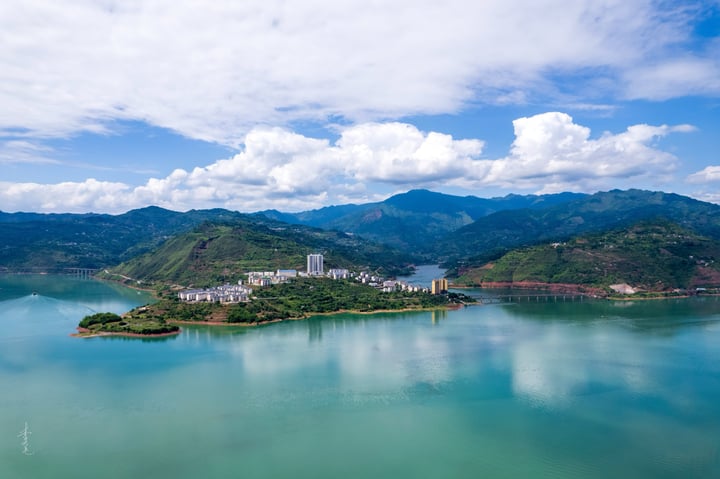 An aerial view of a city nestled between mountains, with a large body of water in the foreground and a cityscape in the background.