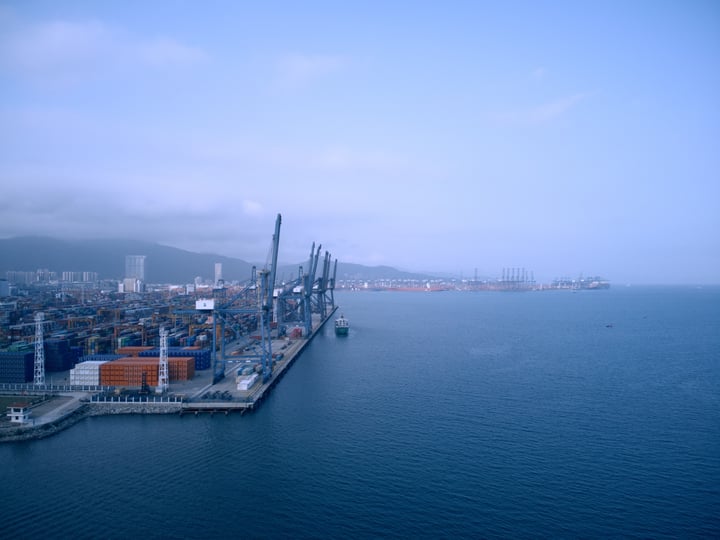 A bustling harbor scene with a large body of water, a city skyline, and a few boats.